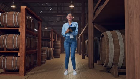 full body side view of an asian female professional worker standing with her tablet in cellar of winery, typing and dissapionted with nodding her shead