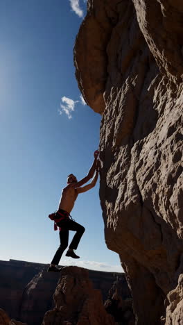 man rock climbing outdoors under a blue sky