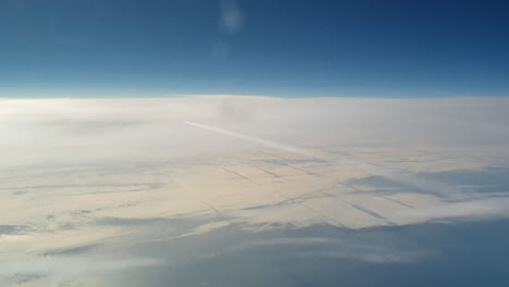 Unglaubliche-Aussicht-Aus-Dem-Cockpit-Eines-Flugzeugs,-Das-Hoch-über-Den-Wolken-Fliegt-Und-Eine-Lange-Weiße-Kondensdampf-Luftspur-Am-Blauen-Himmel-Hinterlässt