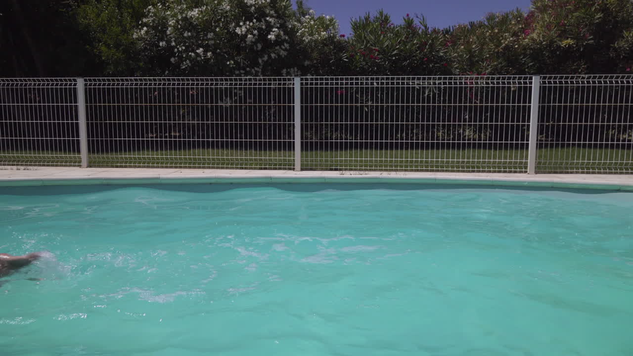 Kvinde svømmer crawl i udendørs swimmingpool.