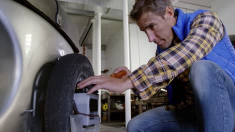 Male-mechanic-repairing-scooter-in-repair-garage-4k