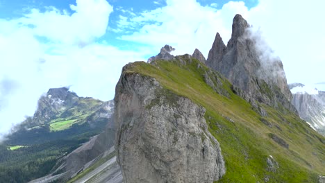 Aufsteigende-Drohnenaufnahmen-Zeigen-Die-Schroffen-Gipfel-Mit-Grünen-Bergwiesen-Der-Dolomiten