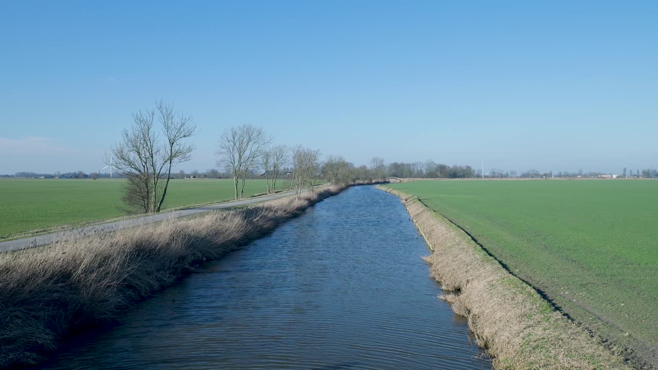 Smal kanal flyder gennem grønne marker i et landskab