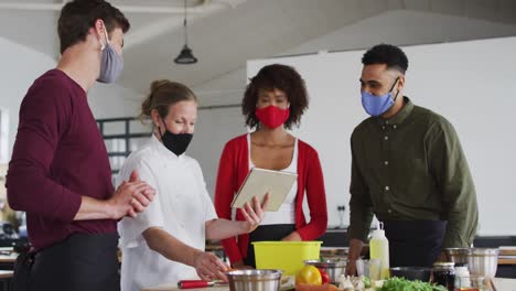 Kaukasische-Köchin-Unterrichtet-Verschiedene-Gruppen-Mit-Gesichtsmasken