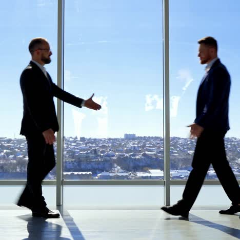 business meeting indoors. businessmen in suits greeting each other against large office windows on the background of a city