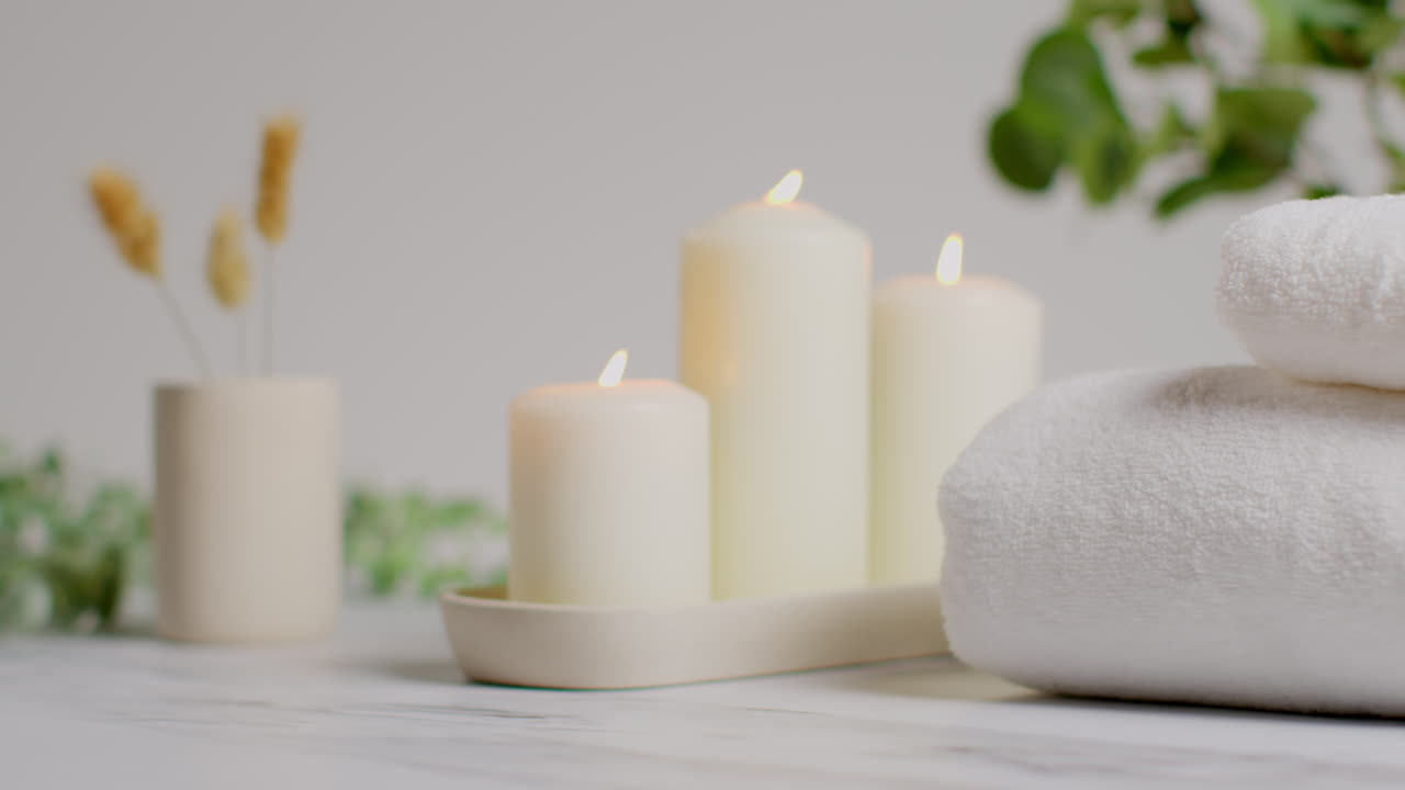 vida muerta de velas encendidas con hierbas secas, plantas verdes y toallas suaves como parte de la relajante decoración del día de spa.