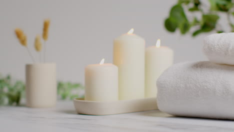 vida muerta de velas encendidas con hierbas secas, plantas verdes y toallas suaves como parte de la relajante decoración del día de spa.