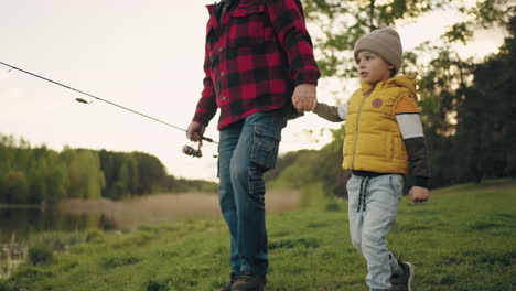 la mañana de la familia de pesca abuelo y nieto están caminando en la orilla del lago niño pequeño y su abuelo