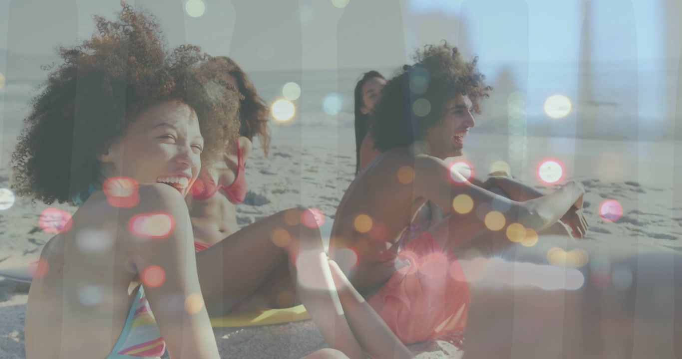 Trio seduto che si china e ride a un segnale fuori campo, con sovrapposizione bokeh su trio in spiaggia per marketing.