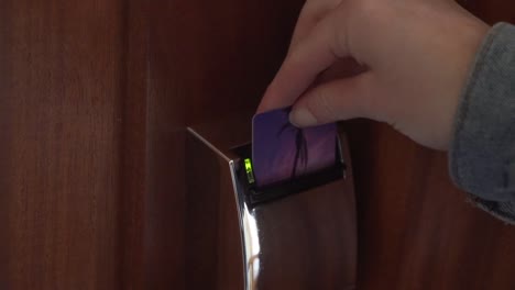 close up of hotel key card unlocking room door by putting in key card