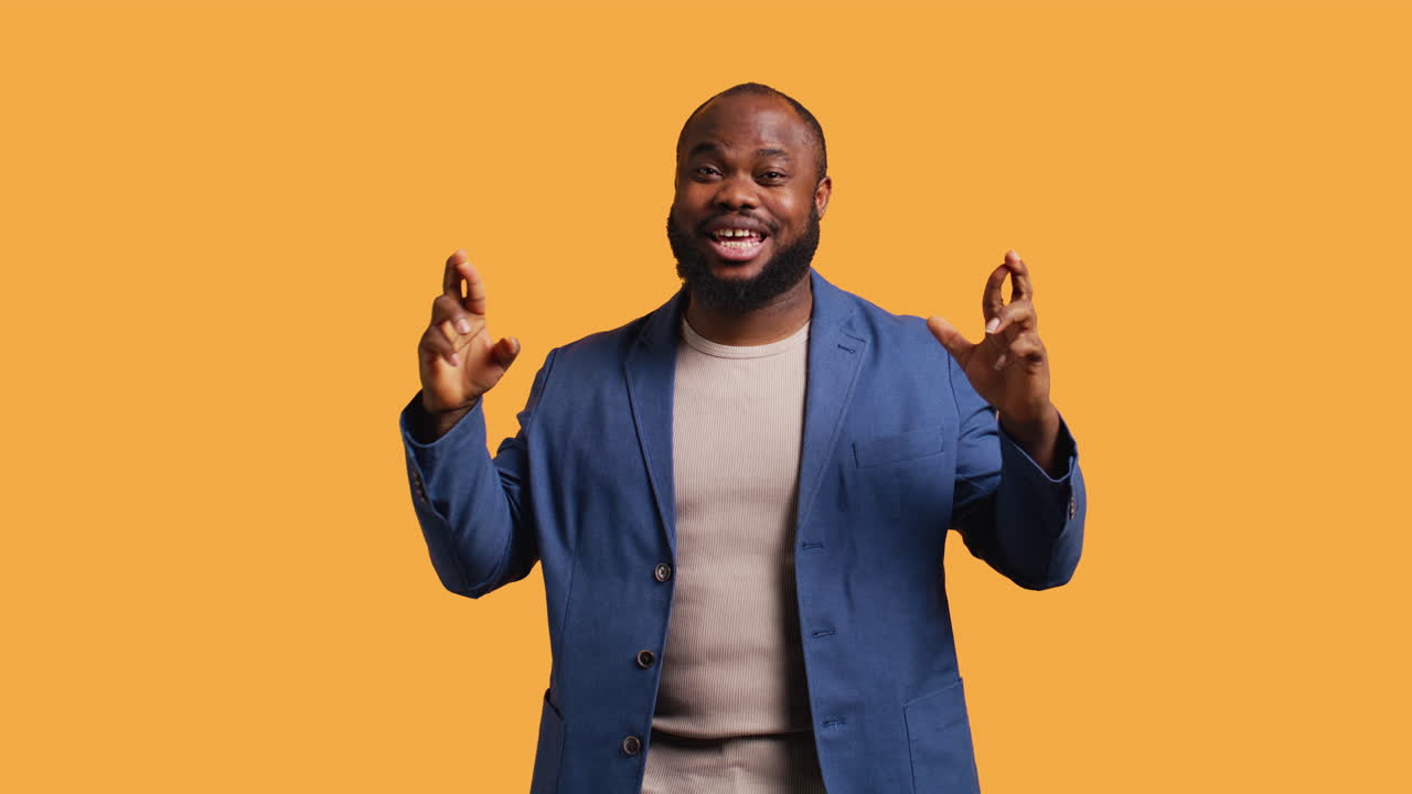 Portrait of upbeat man crossing fingers, making wish, studio background