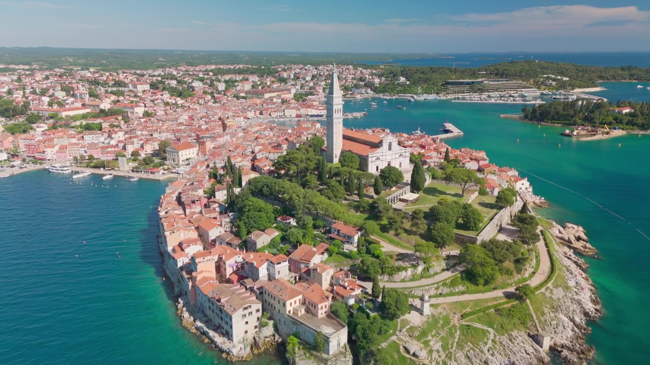 Rovinj'in çatılarından geriye doğru uçan drone, Aziz Euphemia kilisesiyle tepeyi ve Adriyatik Denizi ile kayalıklara karşı uzanan daha geniş eski şehir yarımadasını ortaya çıkarıyor. İstirya, Hırvatistan.