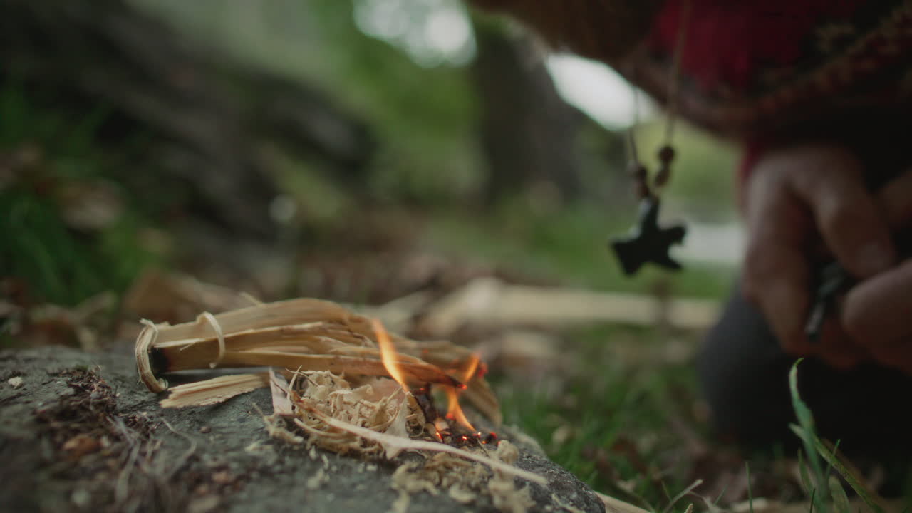 Survivalist Using Ferro Rod and Wooden Feather Sticks to Light Fire