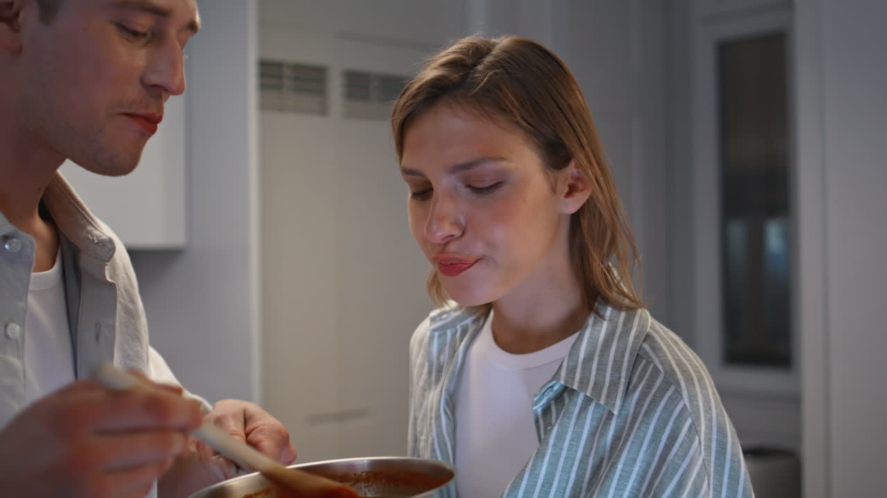 Wife tasting delicious food at home closeup. Man chef cooking dinner for family