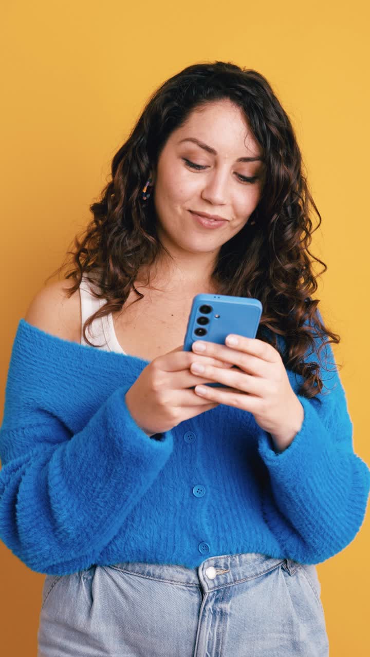 Giovane donna felice sorridente mentre usa lo smartphone