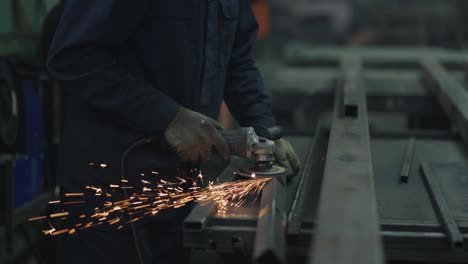 primer plano: un hombre con gafas de protección trabaja con el molido de metal, el pulido y el despojo de estructuras metálicas de acero.