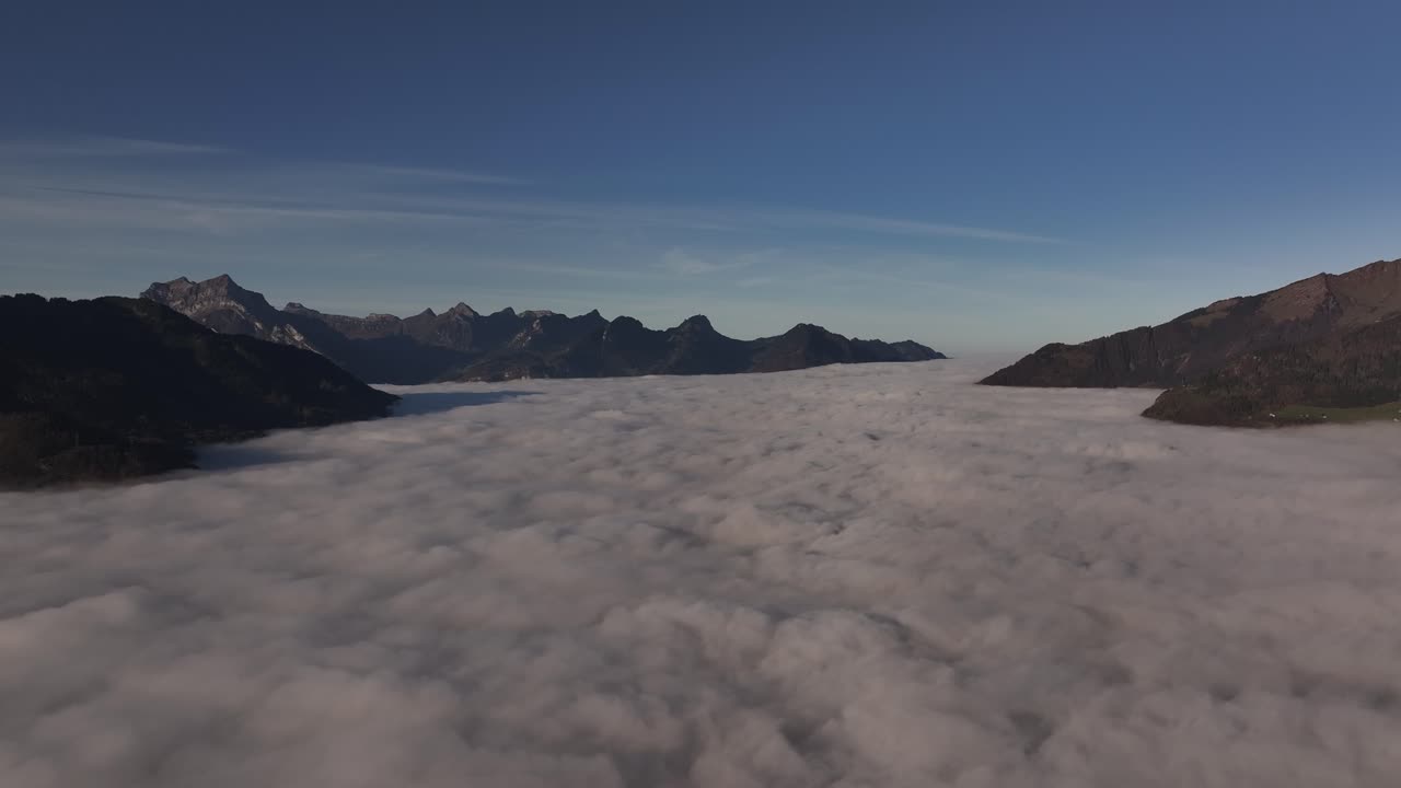 스위스 발렌세의 공중 풍경: 산꼭대기가 아오르고, 조용한 알프스 풍경에 빛이 더해지는 계곡을 고 있는 안개의 바다를 보여줍니다.
