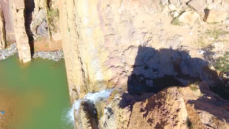 drone shot of a beautiful waterfall between desert mountains in bousaada