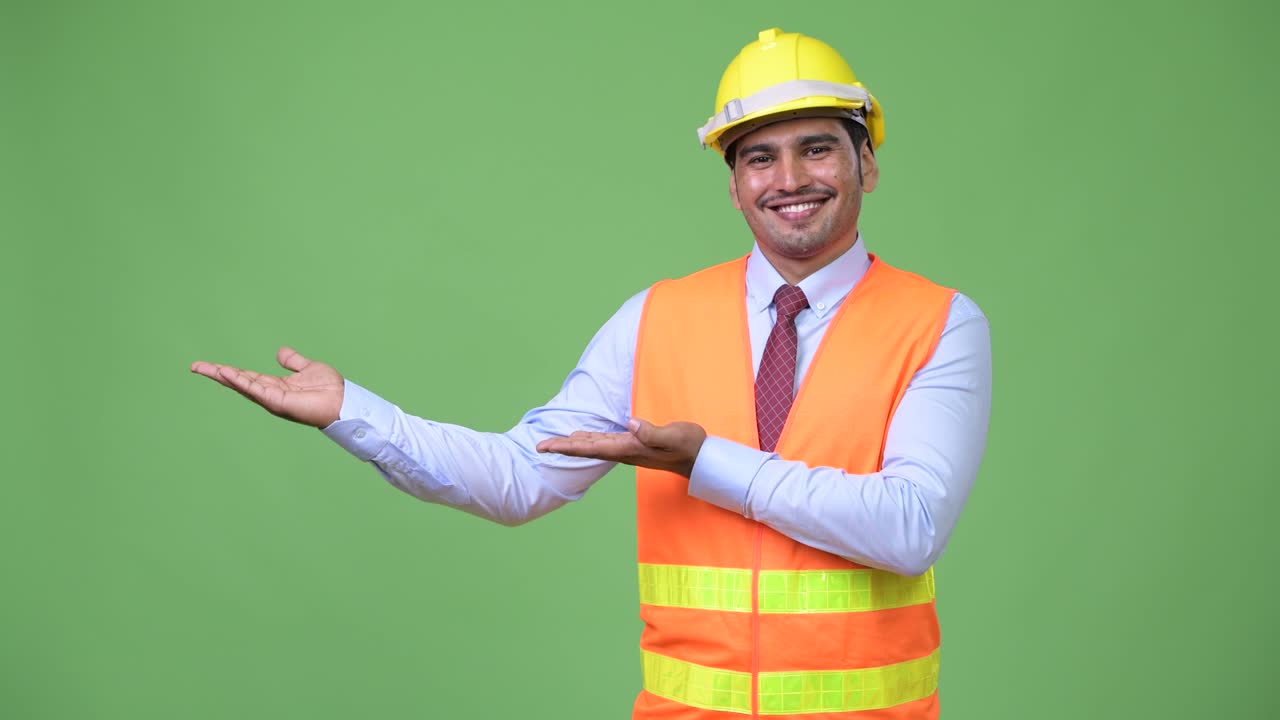 Young handsome Persian man construction worker showing something