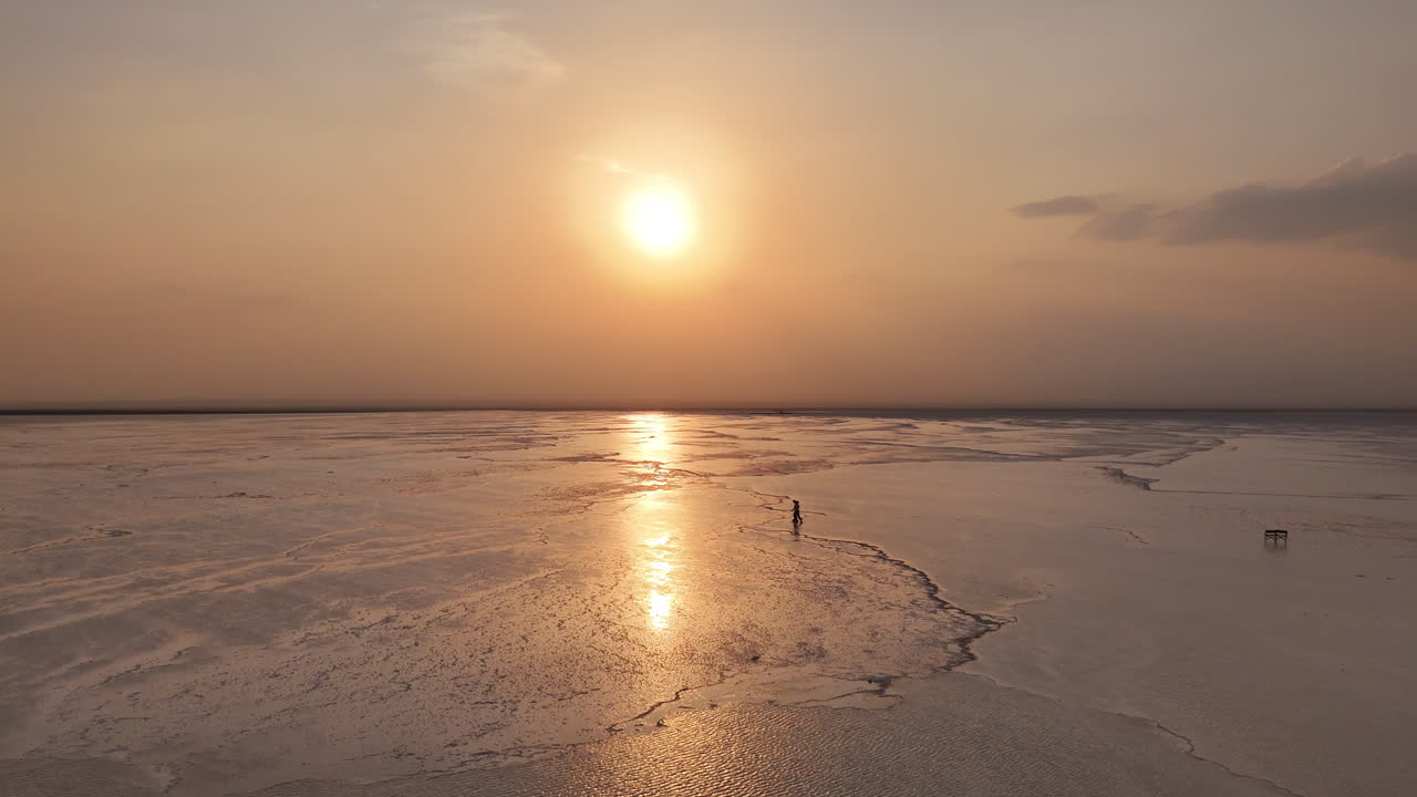 Vista aerea delle saline nella Depressione della Dancalia, dove vaste croste minerali bianche si estendono attraverso la regione dell'Afar in Etiopia. Contro il sole. Persone che camminano sulle saline.