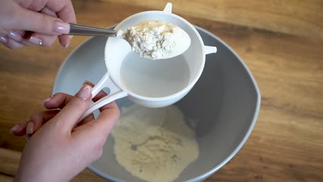 woman puts a spoon of flour into a sieve