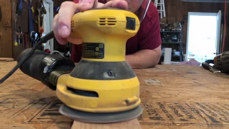 man using sander in wood shop