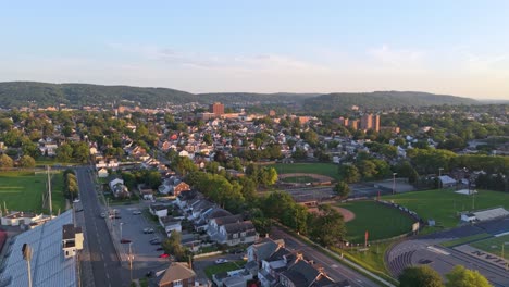 aerial flyover of bethlehem, pennsylvania with sports stadiums, houses, and distant hills under warm sunset light. dolly in