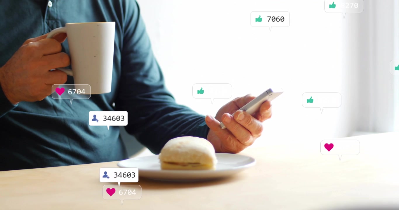 Man tapping phone at table by window, scrolling checking social feed, badges multiplying around bun