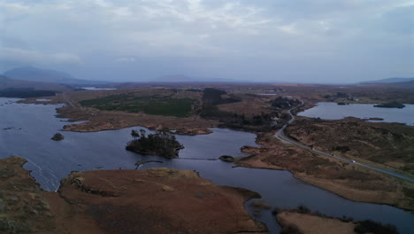 twilight aerial view of derryclare lough, following a winding road with distant headlights piercing the dusk, connemara