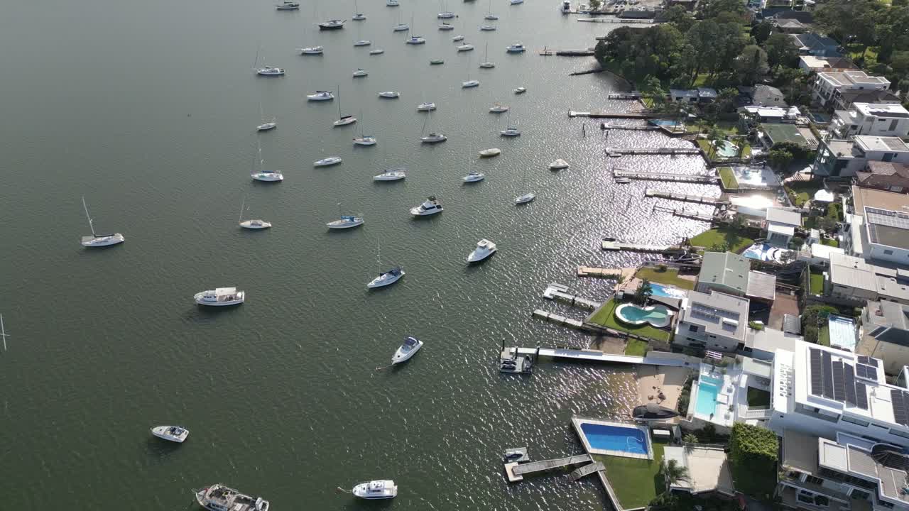 vuelo aéreo sobre casas suburbanas frente al mar, casas, propiedades vecinales con barcos, yates, puerto deportivo de veleros y muelle