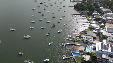 aerial fly over suburban waterfront home, houses, neighborhood properties with boats, yacht, sailboat marina and wharf