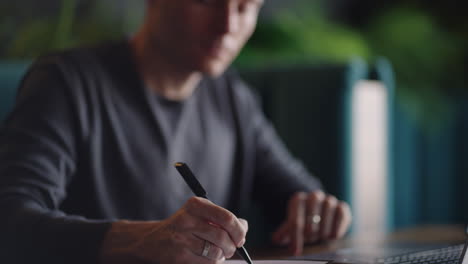 close-up portrait of ponder young man in office. designer plans his work and holding a pencil in his hand. shooting is slow motion from below. thoughtful serious man sit with laptop thinking solution