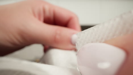 close-up of fingers peeling off a white adhesive bandage with a blurred background