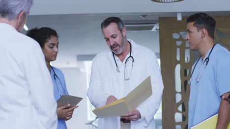 grupo diverso de médicos masculinos y femeninos mirando archivos y discutiendo en la reunión del hospital