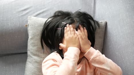 a upset child girl cover her face with hand