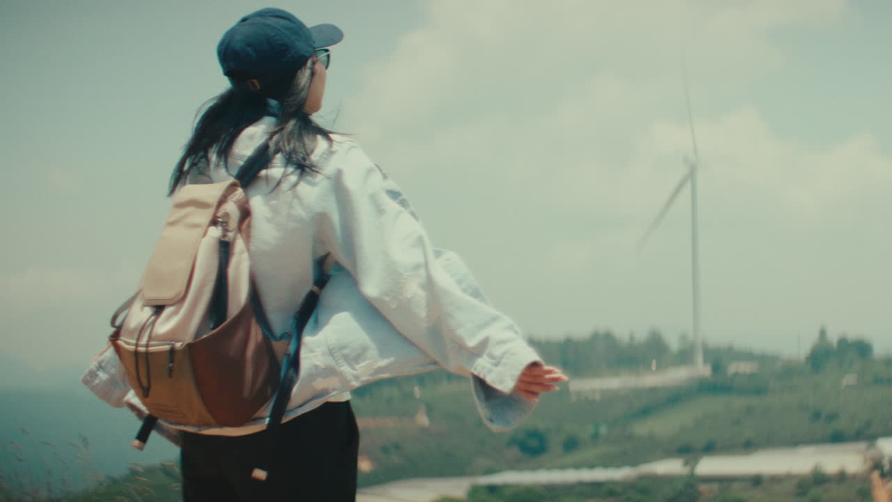Woman enjoying the view from a mountaintop with a windmill in the background