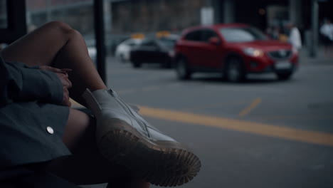 pies femeninas parada de autobús en el fondo de la ciudad. chica esperando un paseo en el área urbana.