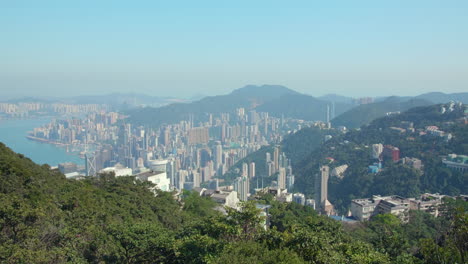 pan shot of hong kong's skyline from the victoria peak summit. views of hong kong island's skyscrapers on a sunny day - the south china sea. cinematic high dynamic range.
