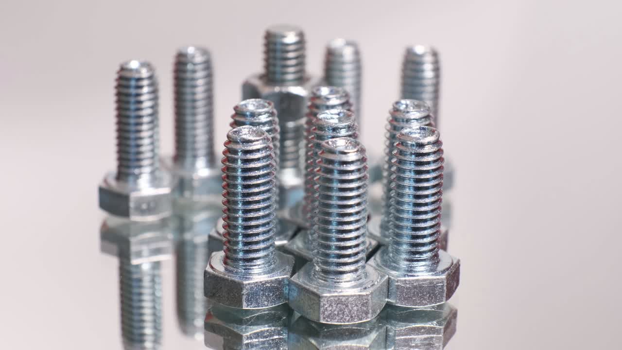 grupo giratorio de tornillos metálicos galvanizados de primer plano. pernos de acero inoxidable aislados en el fondo reflectante del espejo.
