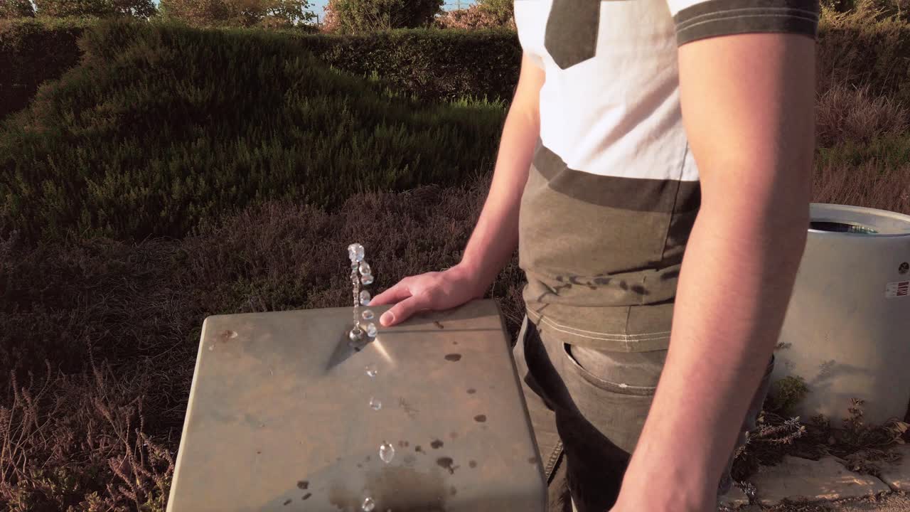 young man drinking water from the trough