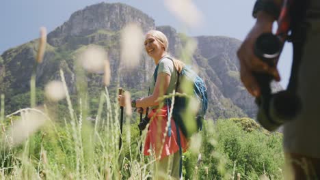 Happy-diverse-couple-hiking-with-backpacks-in-mountains,-slow-motion