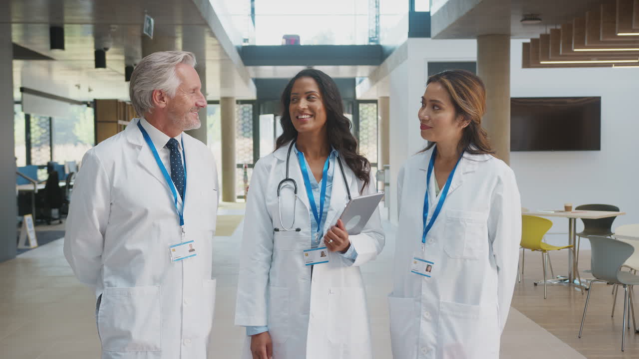 Portrait Of Medical Staff Wearing White Coats With Digital Tablet Having Meeting In Hospital