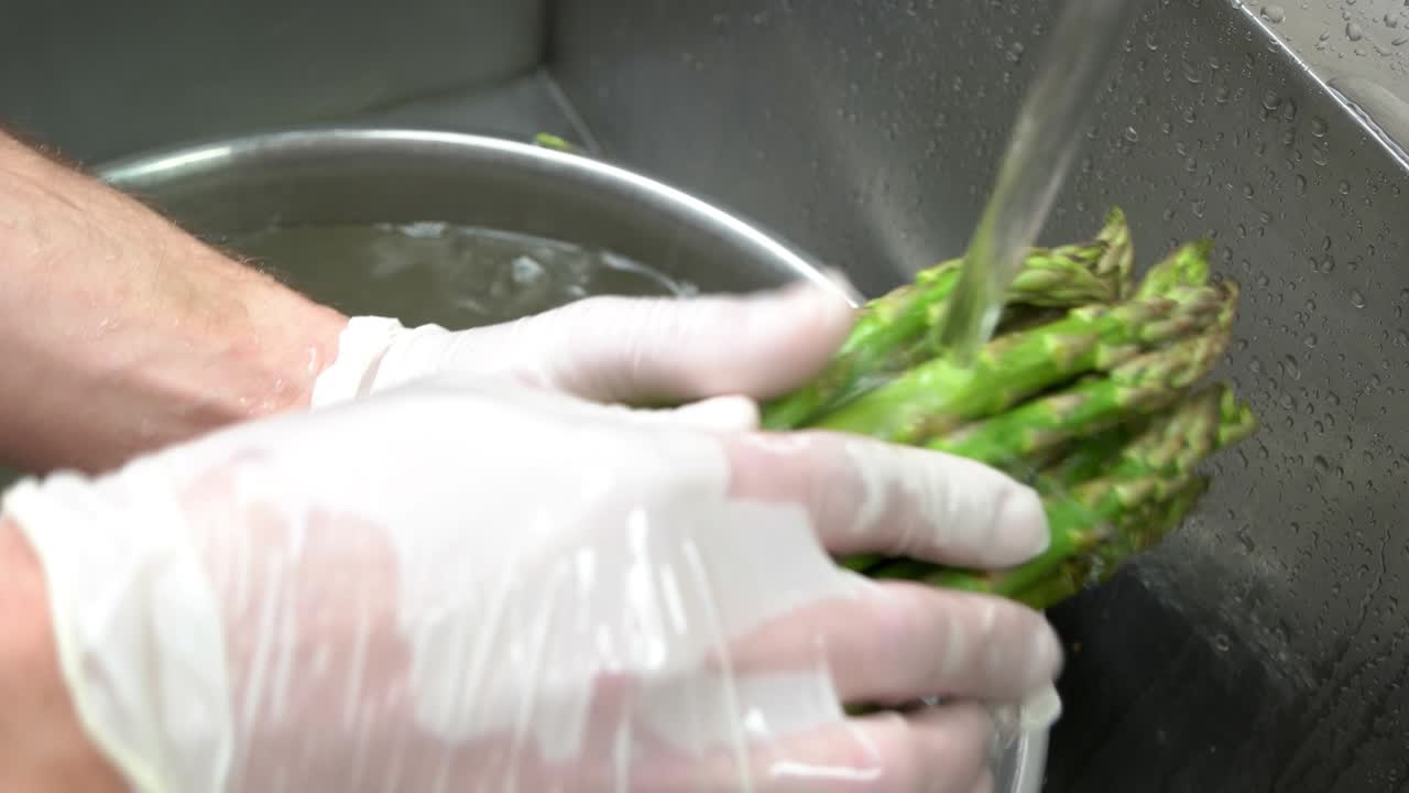 Hands washing asparagus close up.