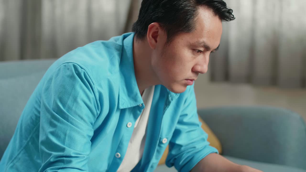 손에 든 지폐를 보고 미소 짓기 전에 노트북으로 타이핑하는 아시아 남자의 클로즈업