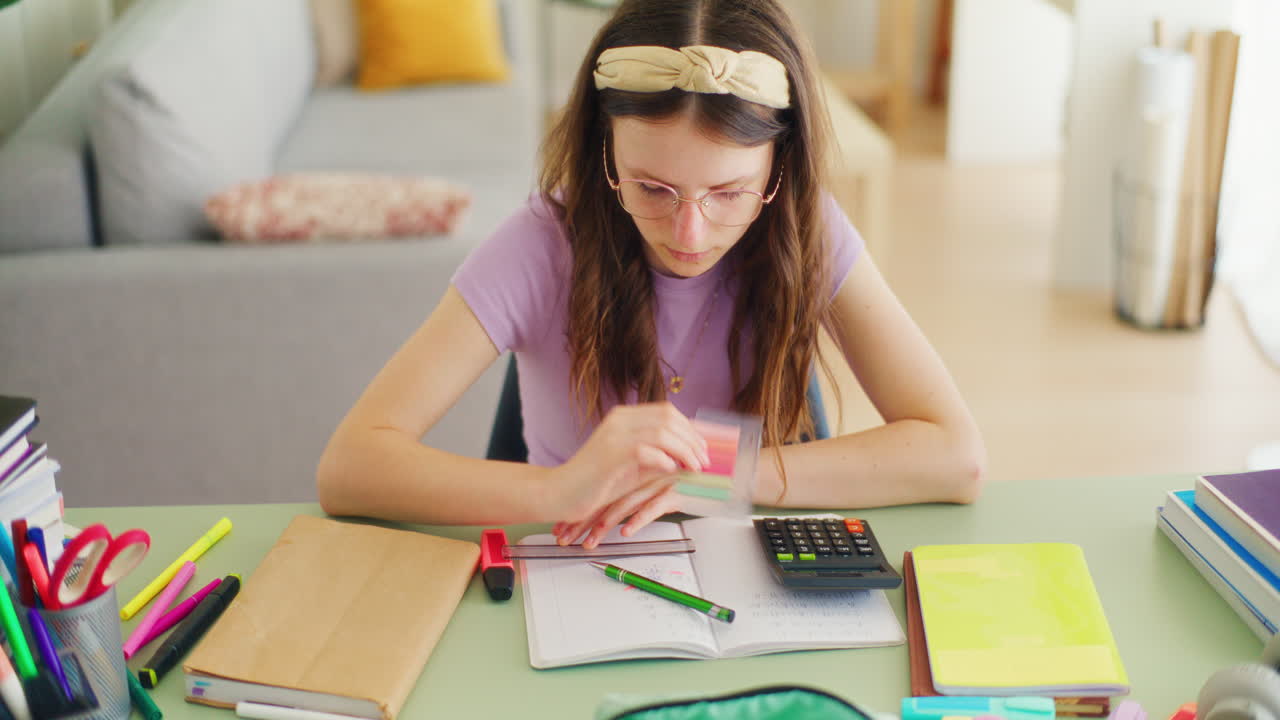 Happy Young Smart Student Doing Math Homework and Writing in a Notebook