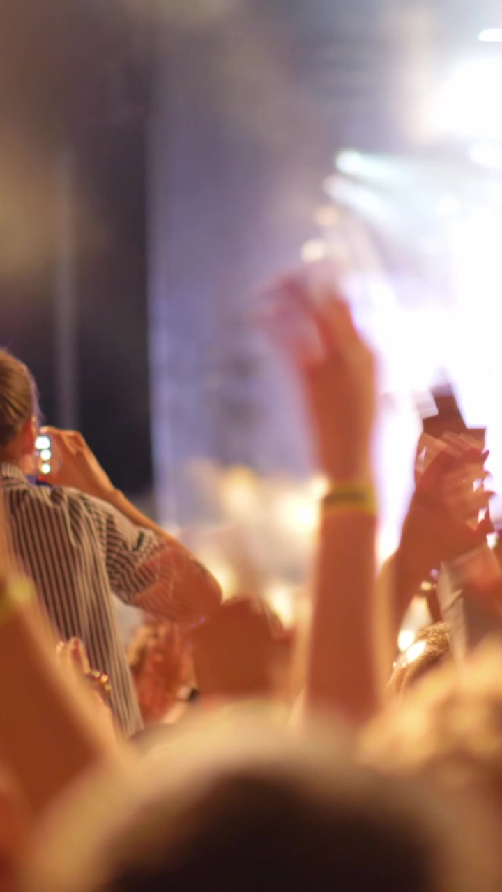 Una folla di fan della musica che agitano le mani a un concerto all'aperto