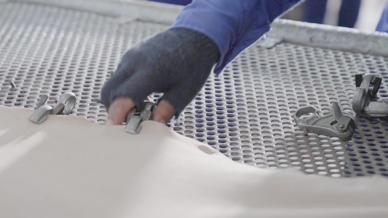 Workers In A Production Factory Taking Clamps Off A Leather Hide During Manufacturing.