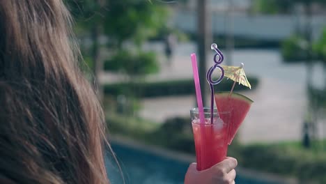 woman-holds-tasty-cocktail-with-watermelon-on-glass-edge