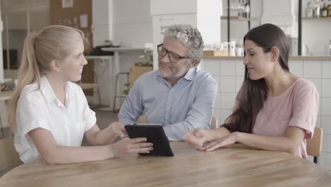 content businesspeople watching data on tablet and talking