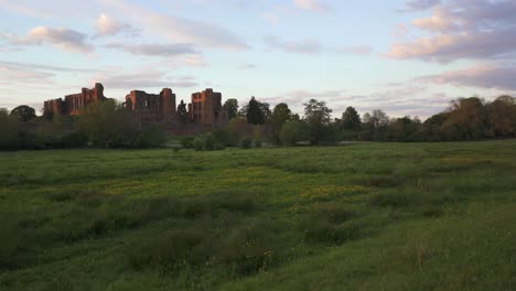 Toma-Panorámica-Lenta-A-Través-De-Los-Campos-Que-Muestra-Las-Ruinas-Del-Castillo-De-Kenilworth-Bañadas-Por-La-Cálida-Luz-Del-Sol-De-La-Tarde.